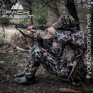 Turkey hunter wearing camouflage chest pack and sitting in backpack seat shooting shotgun